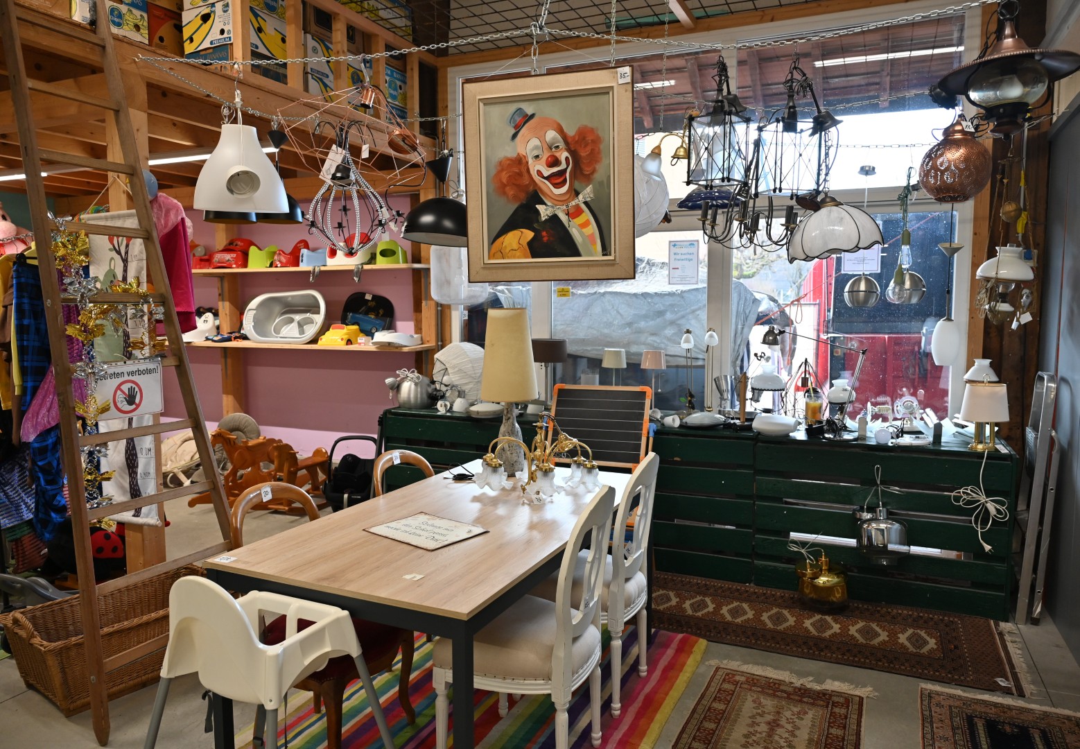 Zwischen Kronleuchter und Kinderstuhl lacht der Clown. Genau diese Mischung macht den Reiz der Brocki aus.